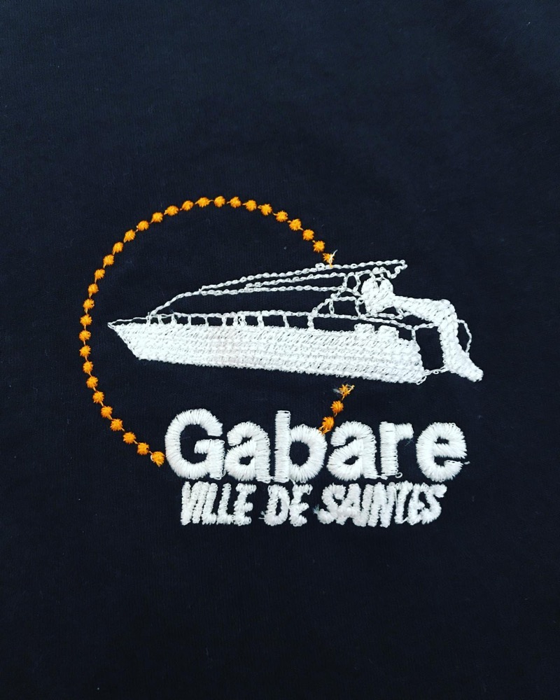 Logo Gabare Ville de Saintes brodé en blanc et jaune sur un textile bleu marine